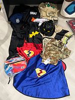 Group view of all costumes, helmet, capes, backpack, camo top
