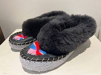Side view of pair showing shearling collar, suede body, rubber sole
