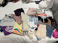 Overall view of all fifteen clothing items spread on bed