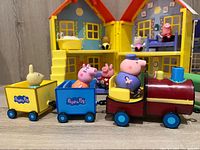 Train set with two wagons and figures in front of yellow playhouse