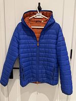 Front view of blue puffer jacket with hood on hanger