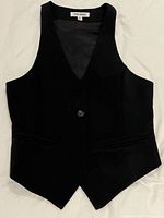 Front view of black vest showing button closure, pockets and pointed hem
