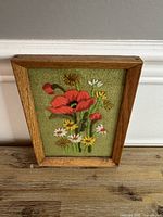 Full view of framed embroidery standing upright