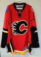 Front view of red Reebok Calgary Flames jersey with tags visible