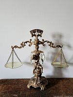 Full view of ornate metal balance scale on wooden surface