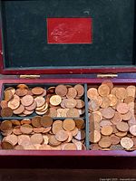 Open wooden box showing three sections filled with Canadian pennies