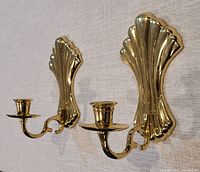 Front view of both brass wall candle sconces mounted on fabric backdrop