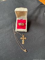 Ring, cross charm on chain, and ring box full view
