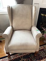 Front view of beige wingback armchair showing upholstery and wooden legs