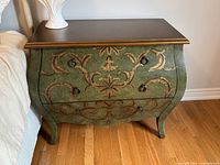 Front view of three-drawer olive-green bombe dresser with scroll design and ring pulls