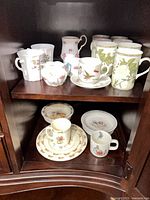 Cabinet view of all china pieces including child sets, mugs, cream and sugar