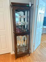 Full view of tall wood and glass display cabinet placed against wall