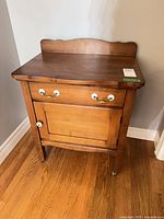 Front view showing drawer with brass-tone pulls and cupboard door