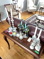Lot overview showing glass and metal candlesticks, coloured glass pieces, votive holders and candles