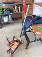 Floor jack with handle and two scissor jacks visible in garage