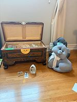 Open carved wooden chest with items, fabric door stops, rosary and figurine in view