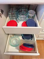 drawer showing multiple round glass bowls with turquoise rims and assorted plastic lids