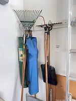 Group of rakes, hoe, shovel, and two camp chairs in bags