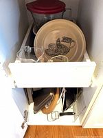 Drawer showing pie dish, glass measuring cups, mixing bowl, baking tins, racks