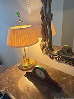 Table lamp and mantel clock on marble surface