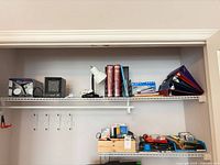 Overall view of closet shelf showing heater, lamp, dictionaries, binders, organizers