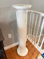 Full view of white fluted composite pedestal next to railing