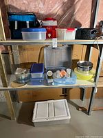 Full lot on metal shelf showing cooler bag, Thermos jug, roasting pan, plastic containers and bowls