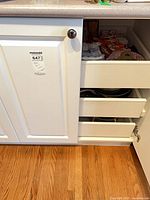 Cabinet interior with kitchen linens visible in upper pull-out shelf