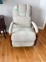 Front view of light beige upholstered recliner chair with wooden arm fronts