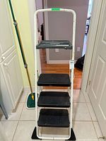 Front view of white metal Cosco ladder with three black steps and grey tray