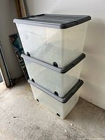 Three stacked clear bins with gray lids and wheels