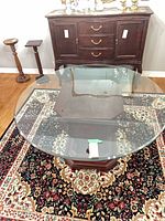 Round glass top table showing wood pedestal base