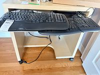 Two keyboards on pull-out tray under desk; Logitech on top, Microsoft beneath