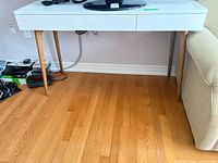 Front view of white desk with wood legs