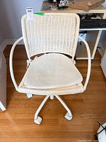 Front view of white wicker swivel desk chair showing five-caster base, seat cushion, overall design