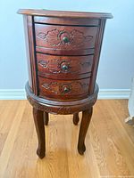 Full view of carved wood side table with three drawers
