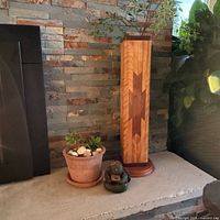 Pedestal with geometric inlay, clay sculpture at base