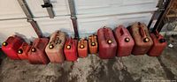 Line of eleven plastic gas cans against garage door