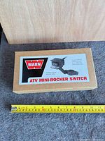 Top of sealed Warn ATV mini-rocker switch box with measuring tape