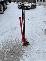 Full view of red and black farm jack standing upright on snowy ground
