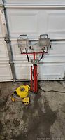 Overall view of work light on stand beside yellow cord reel