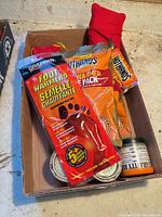 Box containing Grabber Foot Warmers, HotHands packs, fuel cans, black jar, red fabric