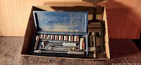 Overall view of socket set in case alongside bench vise in box