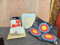 Overall lot showing adhesive target pack, stack of paper targets, folded archery target sheet