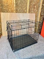 Overall view of black metal wire pet crate with plastic tray inserted