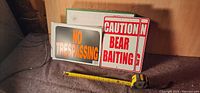 Group view showing No Trespassing and Bear Baiting signs with tape measure for scale