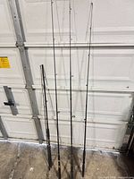 Four fishing rods leaned against wall showing full length