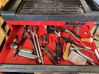 Overall view of red drawer containing pliers, wire stripper, spring and other tools