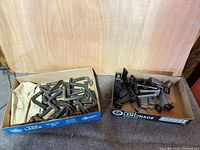 Two open cartons containing metal screw steps and flat bracket steps