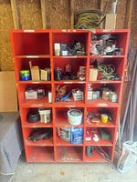Front view of red cubby shelving unit loaded with workshop items